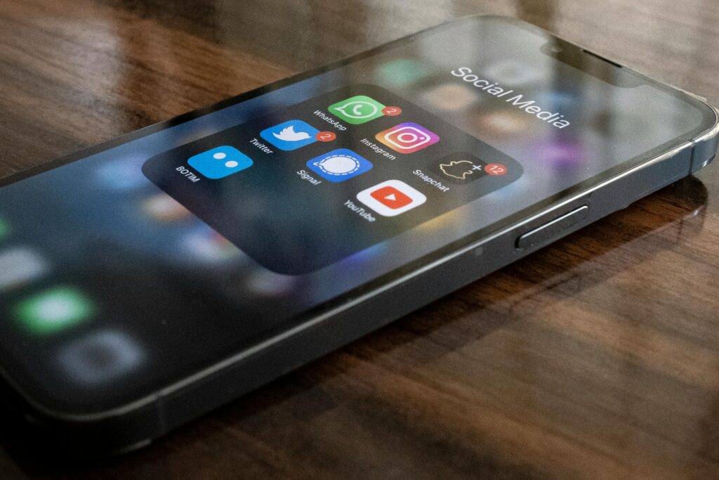 Close-up of smartphone on table showing various social media app icons including WhatsApp and Instagram.